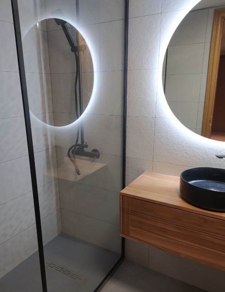 Baño con bañera y espejos redondos retroiluminados