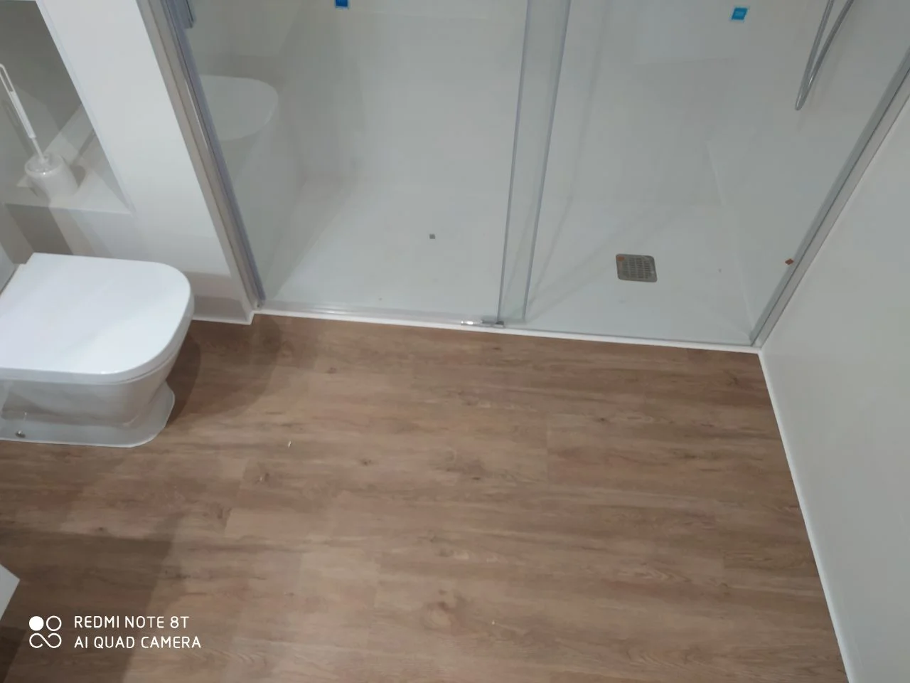 Baño reformado con plato de ducha a ras de suelo y tarima