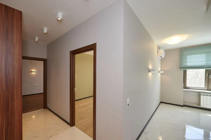 Pasillo terminado con puertas de madera y falso techo con focos