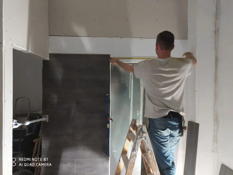 Operario colocando una placa de revestimiento en la pared de una cocina
