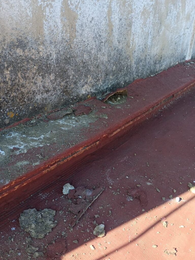 Terraza antes de la reforma con la impermeabilización deteriorada y humedades en el muro
