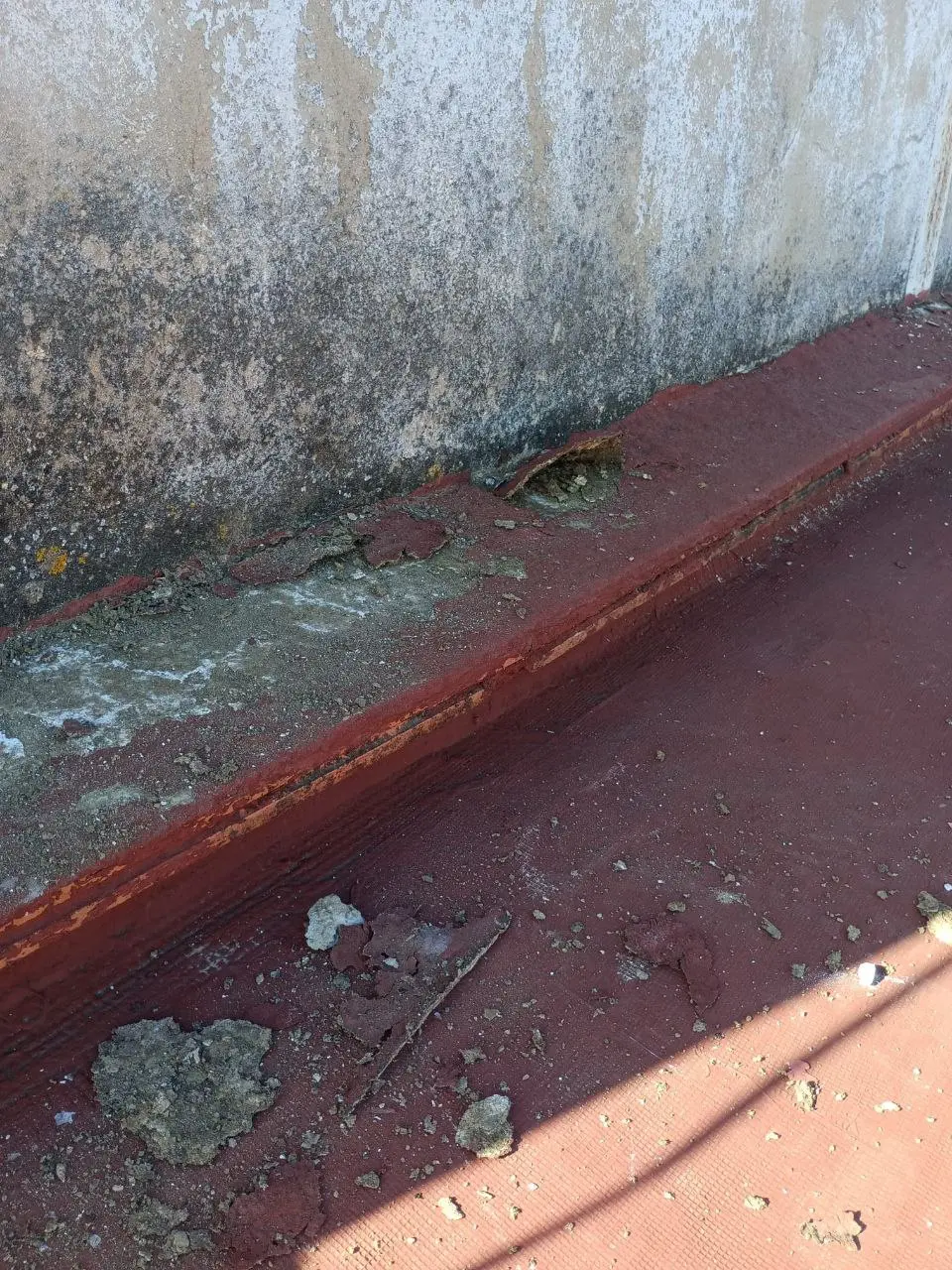 Terraza antes de la reforma con la impermeabilización deteriorada y humedades en el muro