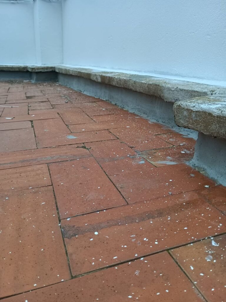 Terraza antes de la reforma con pavimento cerámico levantado y humedad en el peto