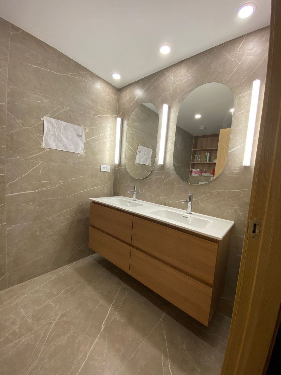 Baño reformado con revestimiento porcelánico efecto mármol y mueble suspendido de doble lavabo