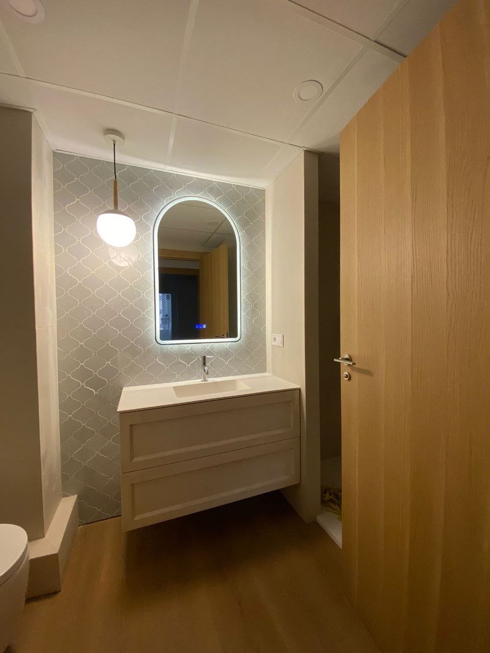 Aseo reformado con lavabo sobre encimera, carpintería de madera y lámpara colgante