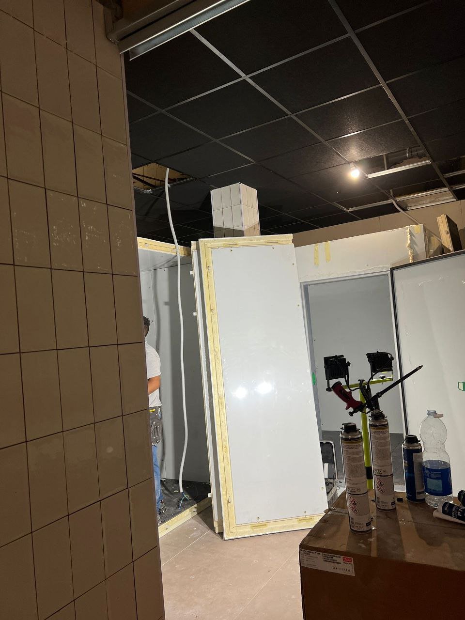 Interior de local durante la reforma con alicatado colocado y falso techo desmontado